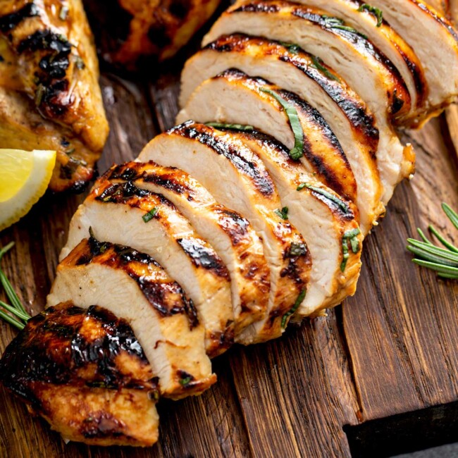 Sliced balsamic marinated chicken breast on a wooden cutting board