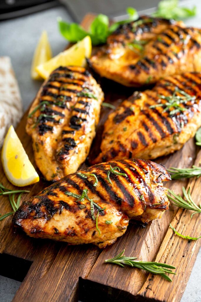 Top view of 4 Grilled Chicken Breasts on a wooden board 