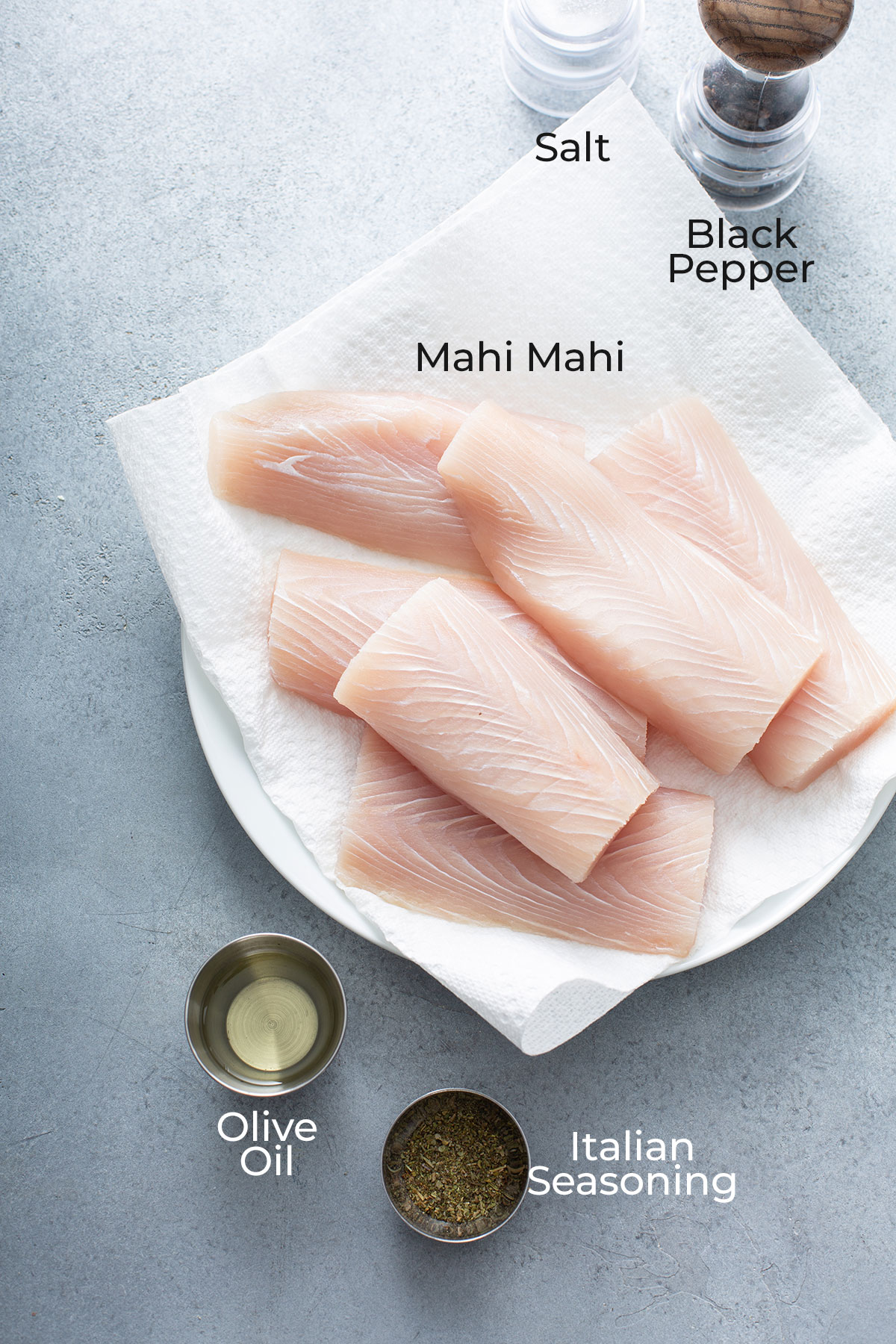 Fish fillets, olive oil and seasonings on a gray surface.