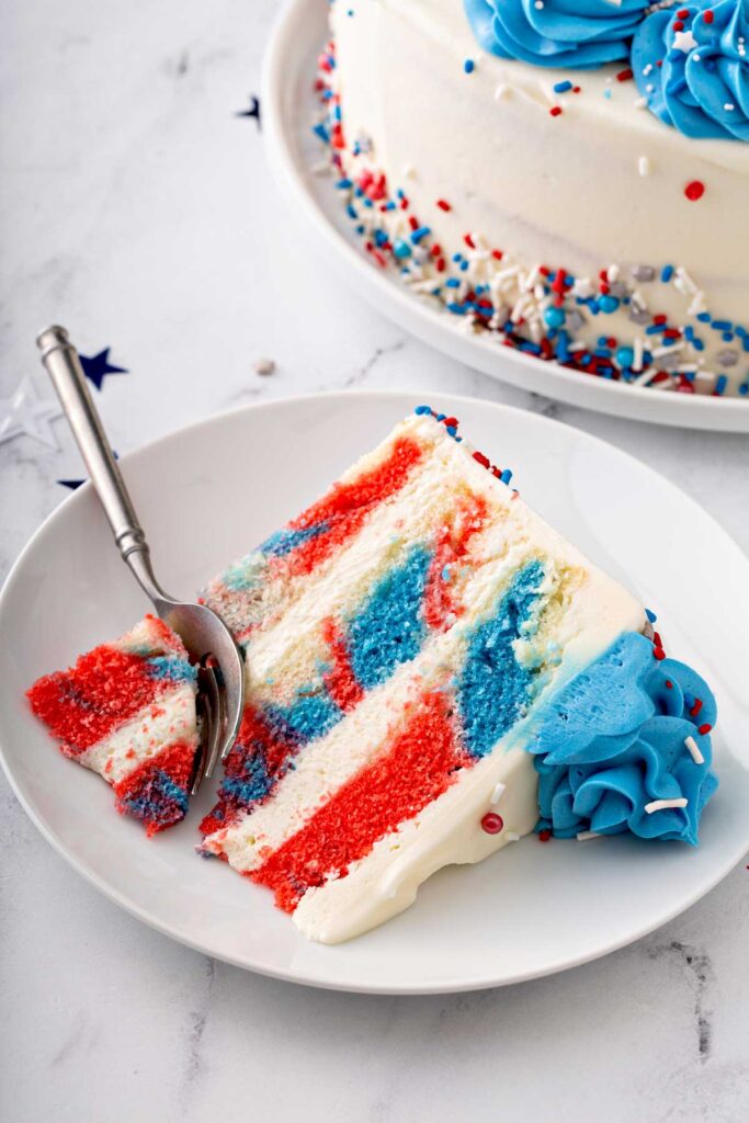 Beautiful slice of frosted, layered red white and blue cake on a plate
