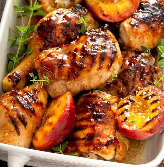 Juicy and sticky glazed chicken legs and thighs in a white ceramic pan