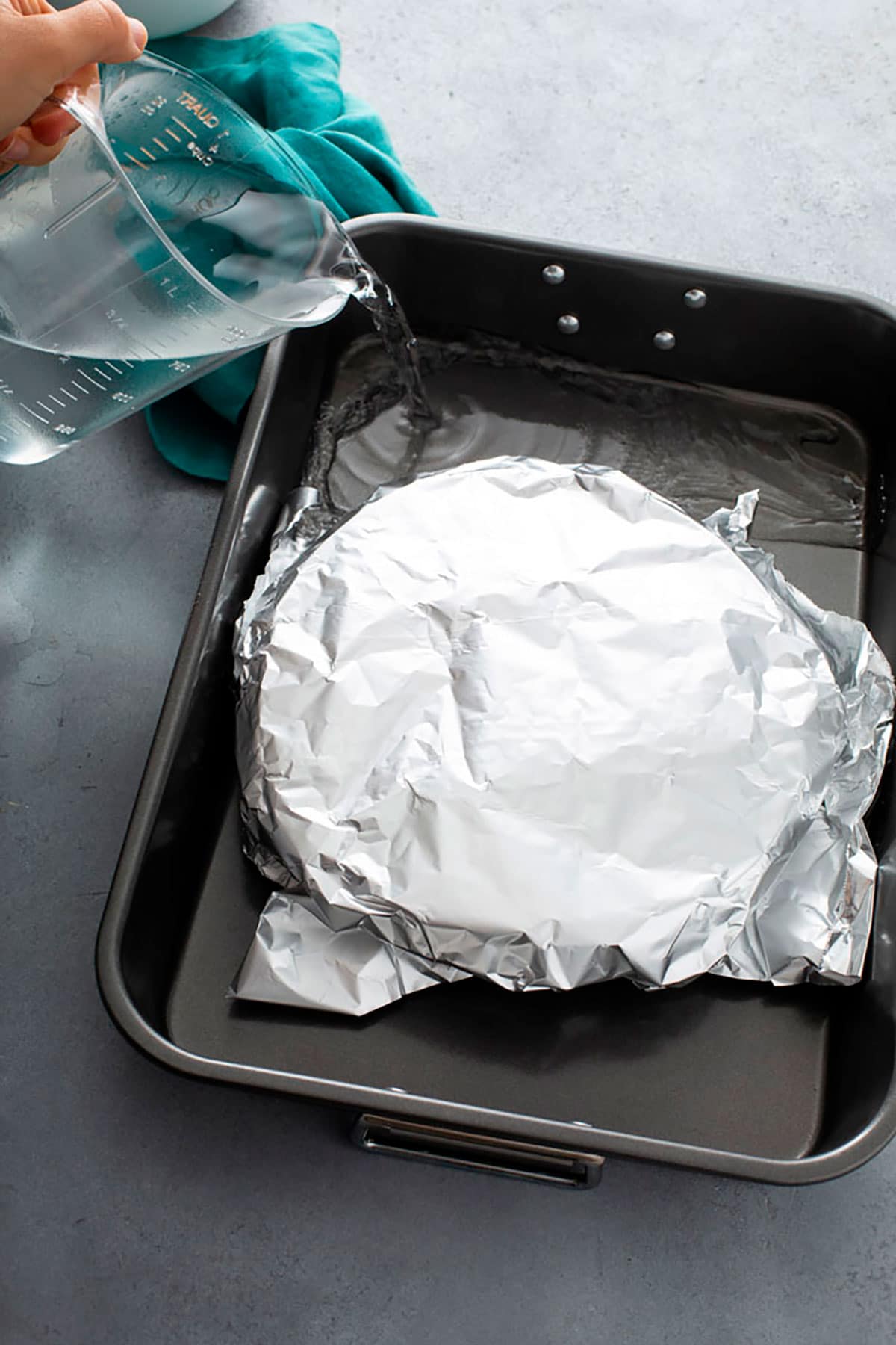 Pouring water into a large baking pan to make a bain marie to bake a flan