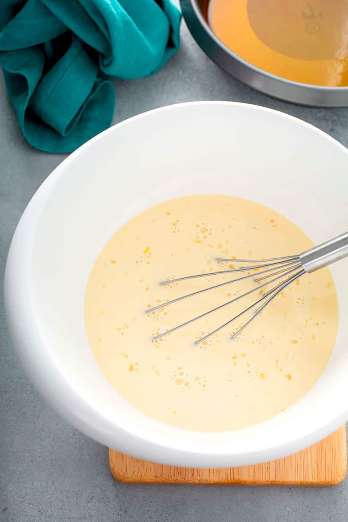 Mixing custard for flan in a white bowl.