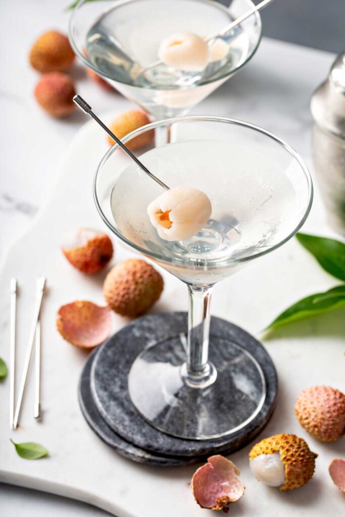 two lychee martinis with lychee on a pick