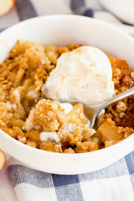 A bowl of homemade apple crisp topped with vanilla ice cream