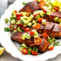 Blackened salmon recipe with chopped salad of tomatoes, avocado and cucumbers on a white platter