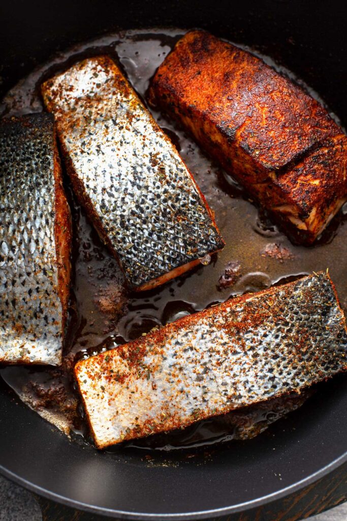 Fish fillets pan searing in a cast iron skillet.