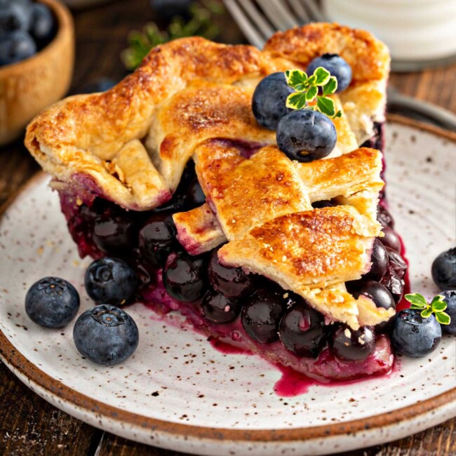 A piece of easy fresh blueberry pie with a golden brown flaky crust on a plate