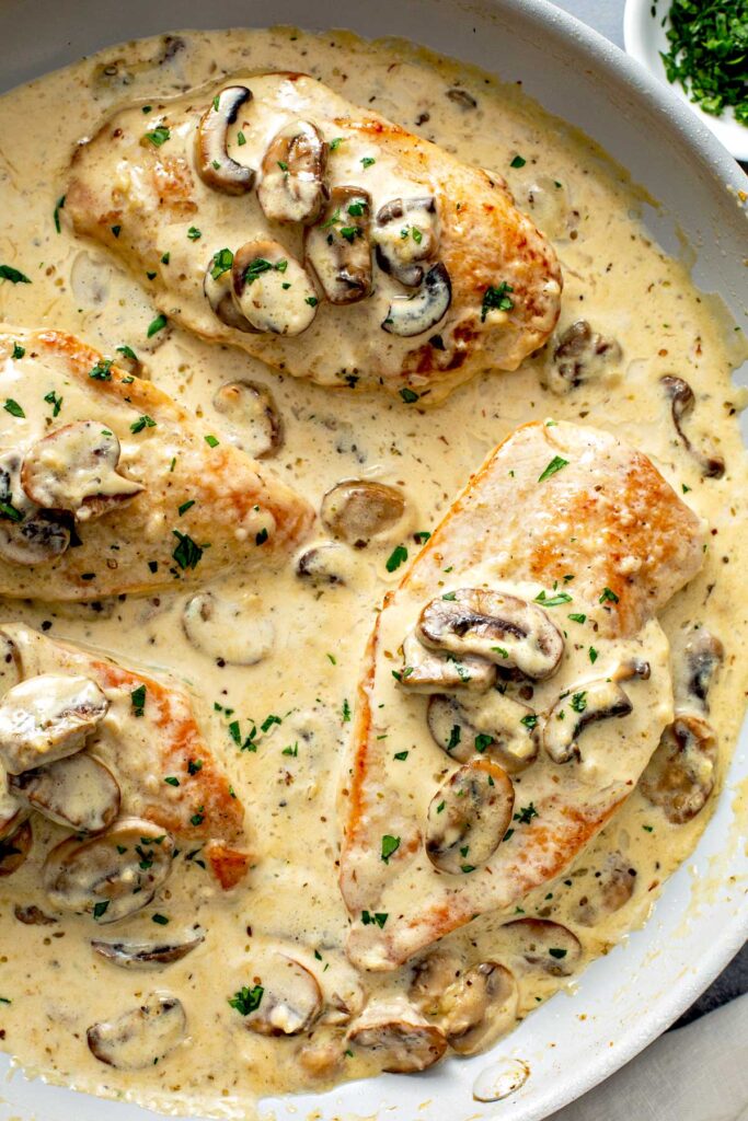 Creamy chicken and mushroom sauce cooking in a skillet