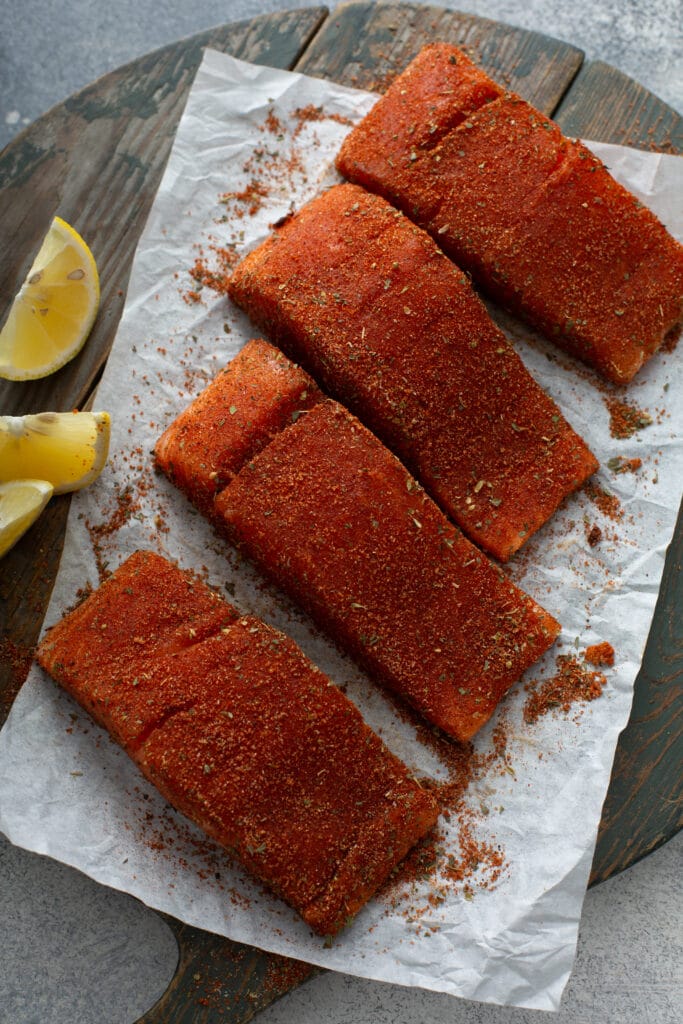 Fillets of salmon seasoned with blackening spice mix on a piece of parchment paper.