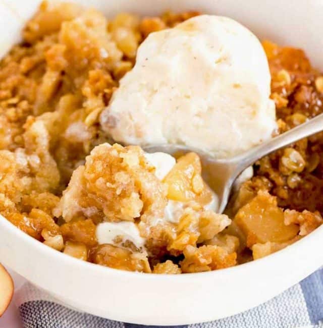 A bowl of homemade apple crisp topped with vanilla ice cream
