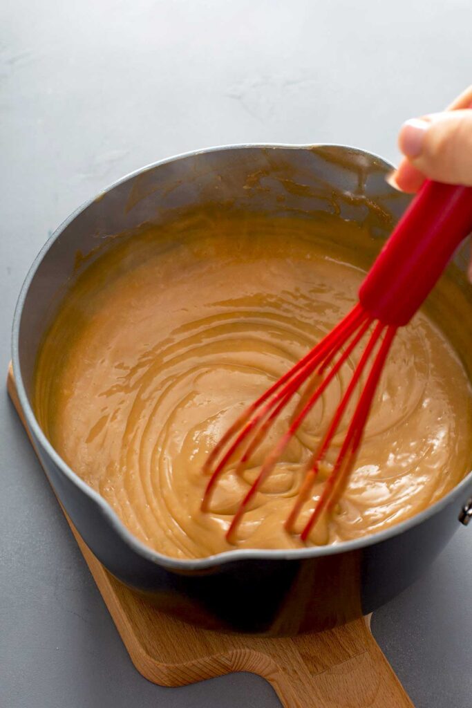 Creamy and silky butterscotch on a sauce pan with a wisk.