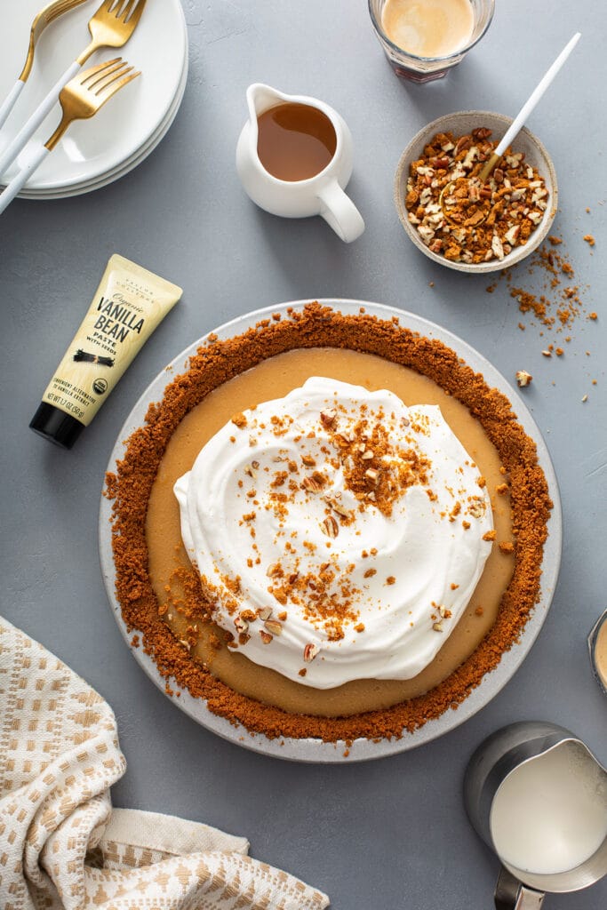 Photo of a butterscotch pie topped with smooth whipped cream and cookie crumbs and pecans