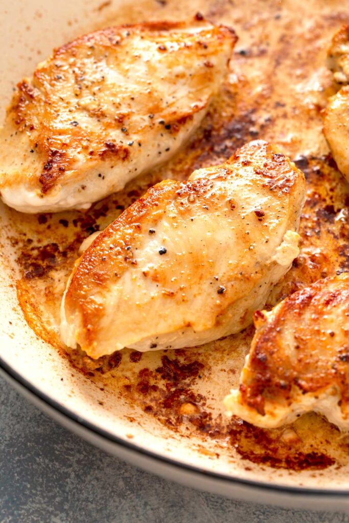 Golden brown seared boneless 
 and skinless chicken breasts in a skillet.