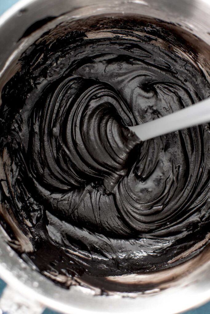 Black Cocoa frosting in a large bowl with a gray spatula.