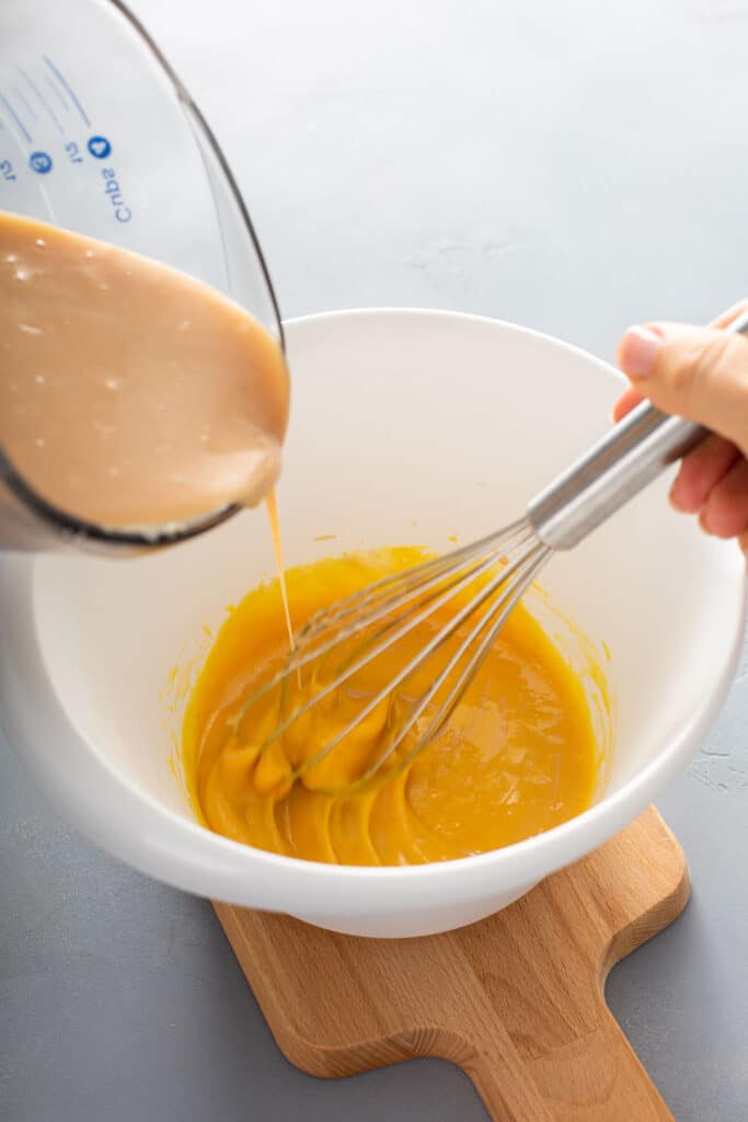 pouring the caramel sauce into the egg yolks