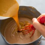pouring the caramel and egg yolks mixture into the saucepan