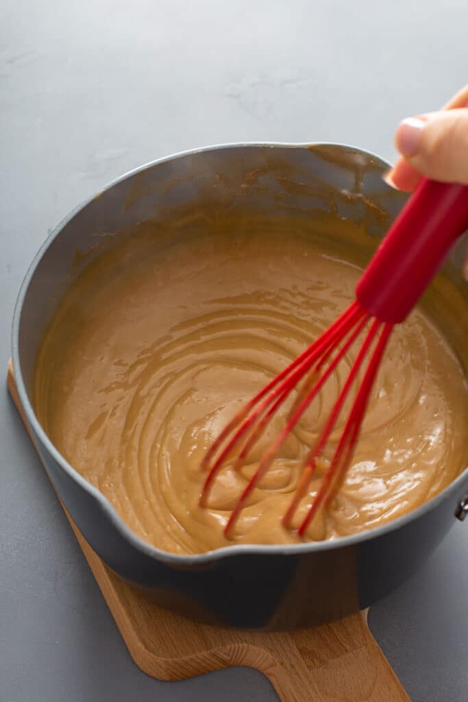 stiring the butterscotch sauce with a red whisk