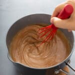 stiring caramel sauce with a red whisk