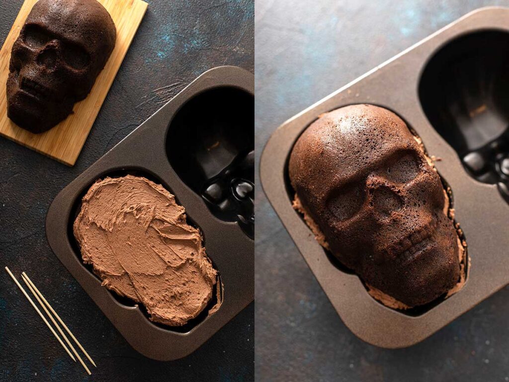 Half of a cake shaped like a skull covered with chocolate buttercream  in a skull baking pan