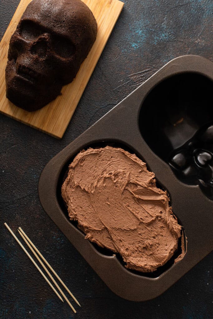 chocolate buttercream spread over one half of the skull cake