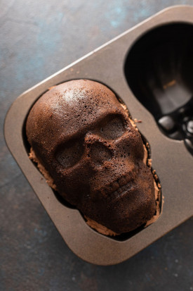 chocolate skull cake with buttercream on the middle in a skull shaped pan