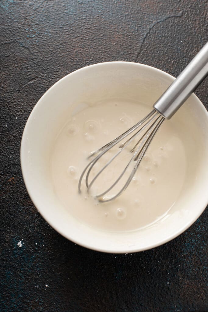 sugar glaze on a white bowl with a whisk