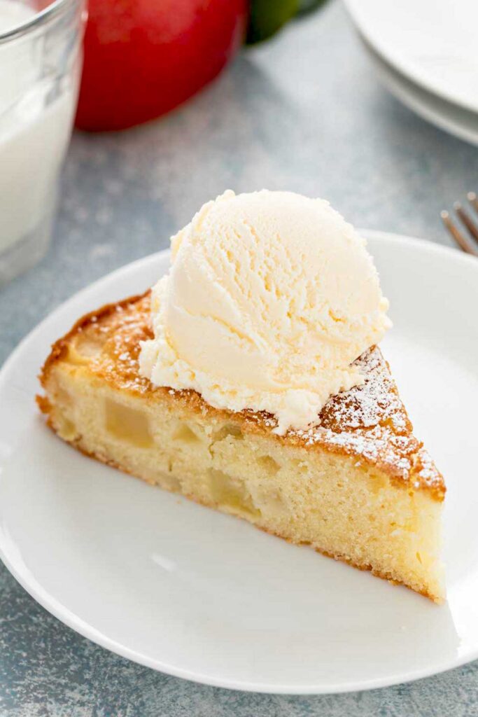 A slice of apple cake topped with vanilla ice cream