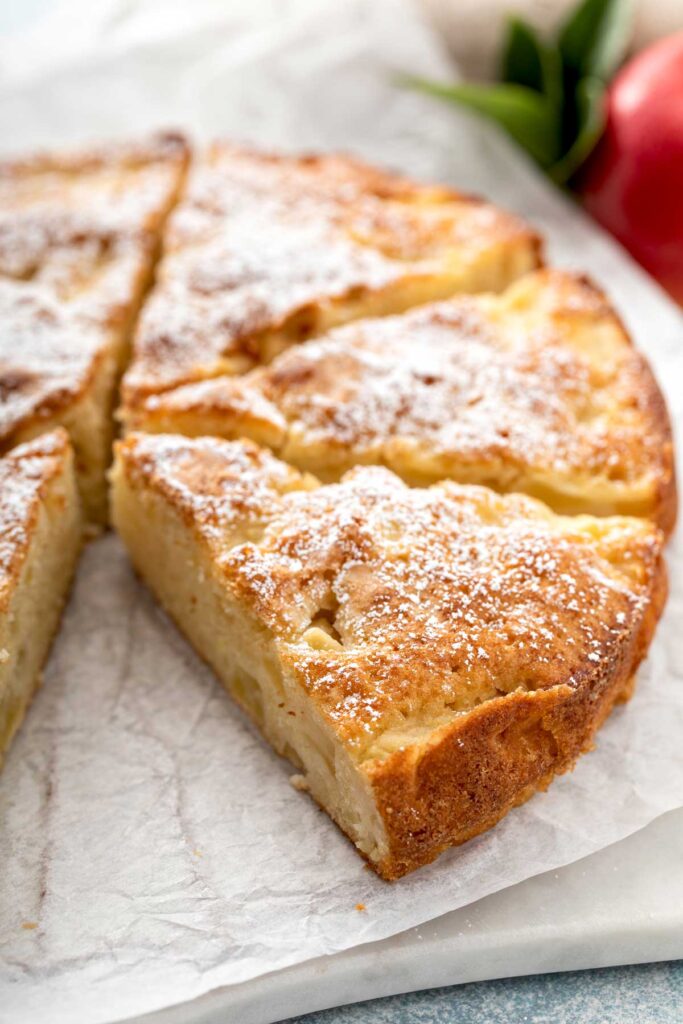 Apple cake cut into big slices on a piece of parchment paper