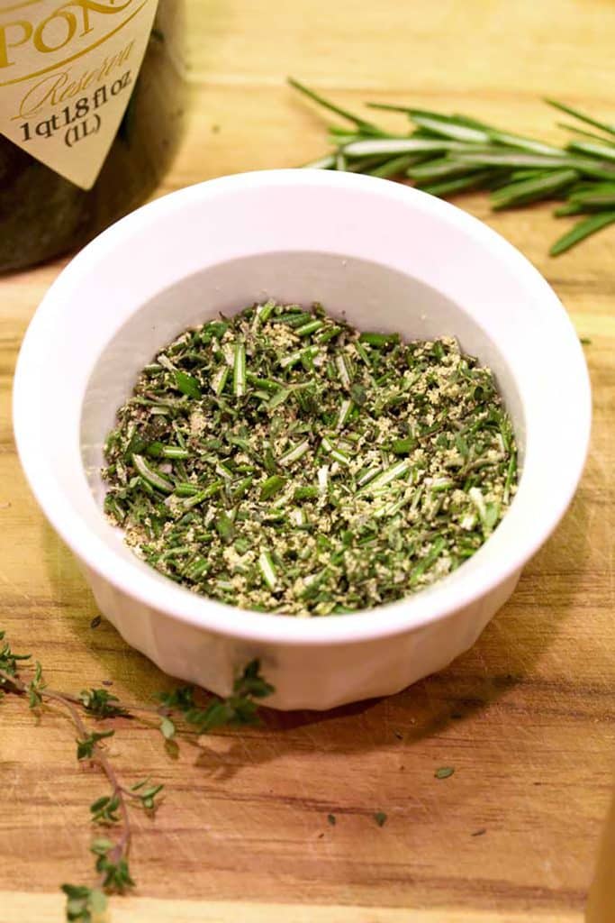 a mix of herbs in a small white bowl