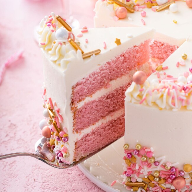 Luscious pink champagne cake getting served with a cake server.