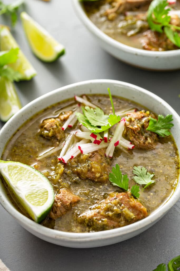 Pork pieces stewed in a green chile sauce served in a white bowl