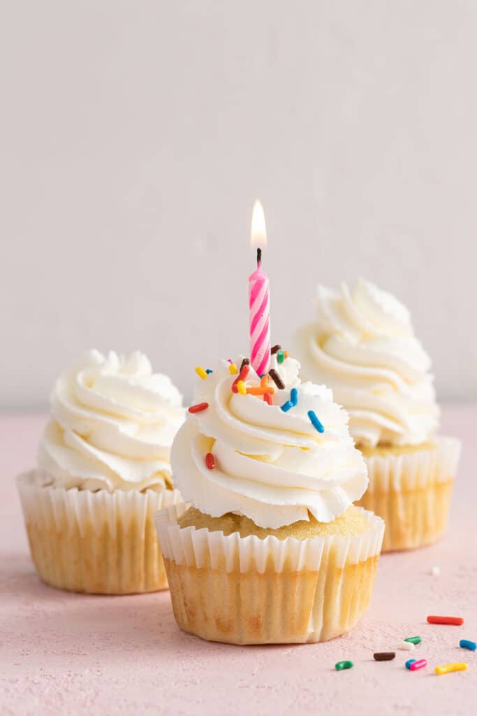 Frosted vanilla cupcake with a birthday candle lit.