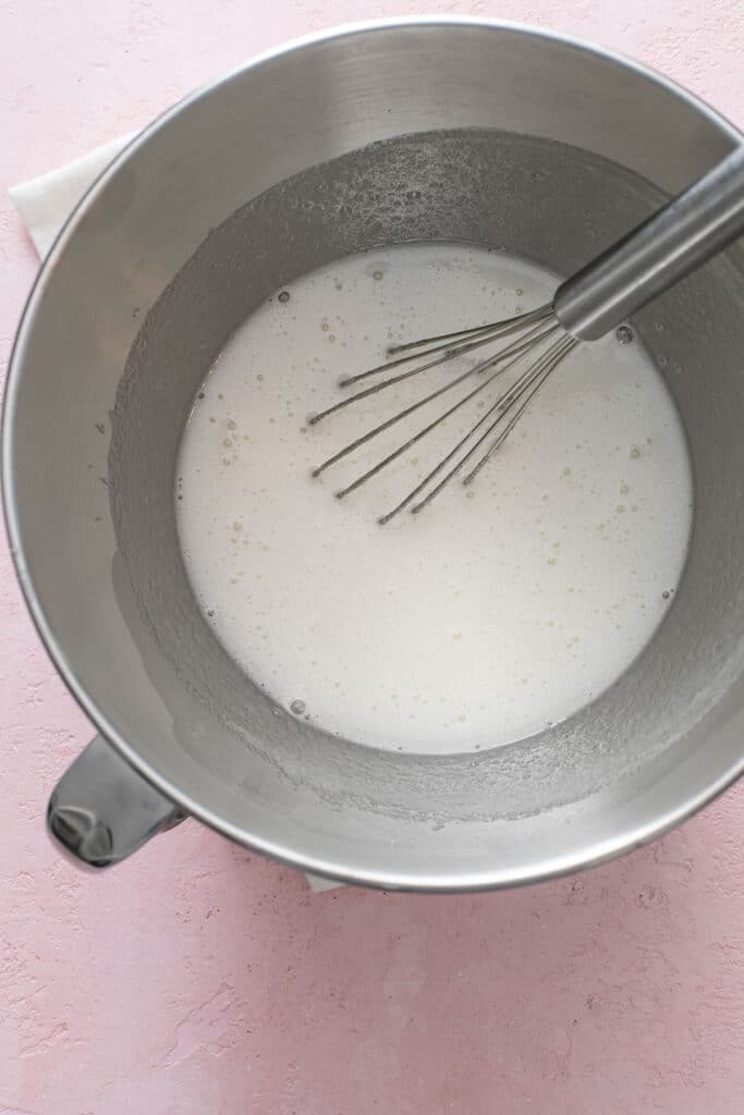 Egg whites and sugar lightly whisked and foamy in a metal mixing bowl