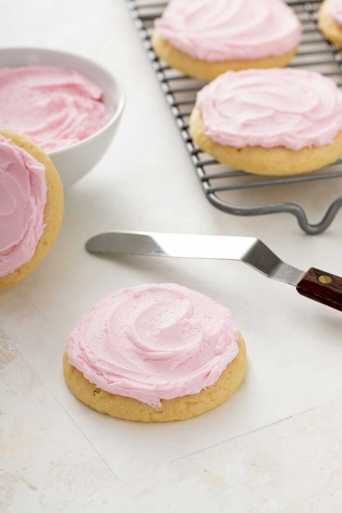 A freshly frosted cookie next to a small spatula.