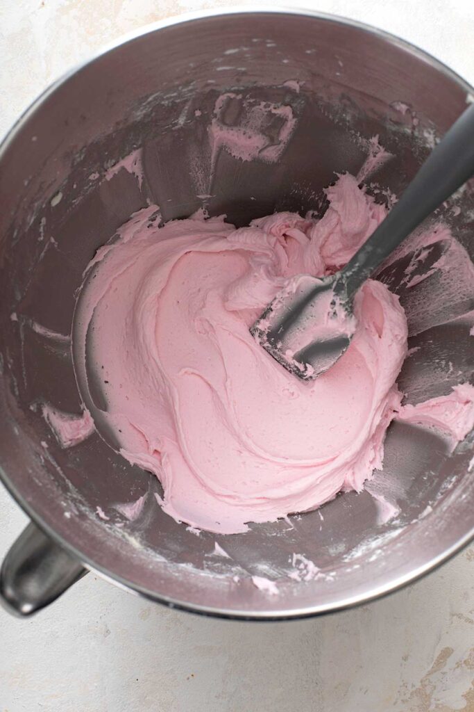 Creamy and smooth pink frosting in the bowl of a mixer.