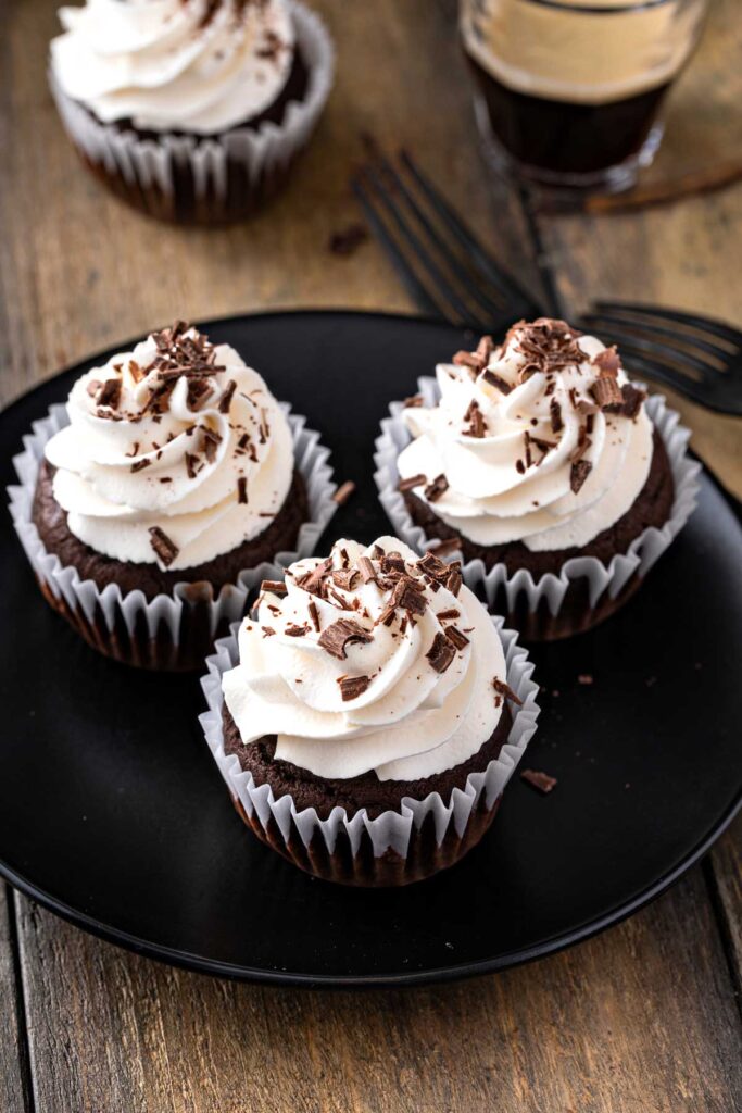 Chocolate cupcakes with Irish stout frosted with whipped frosting on a black plate
