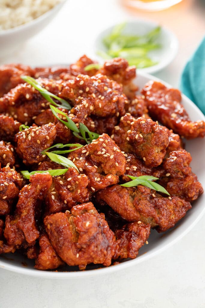A plate filled with crispy chunks of fried chicken tossed with a sweet, sour and spicy Gochujan Korean sauce