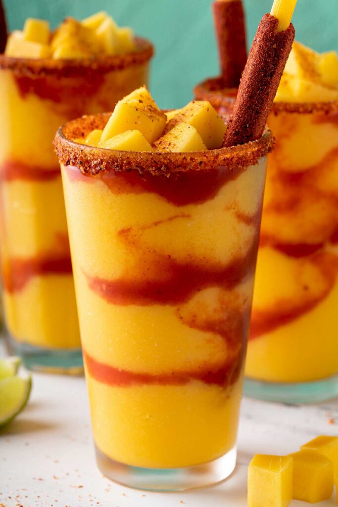 Closeup of a mangonada frozen drink in a glass with a candy tamarind straw
