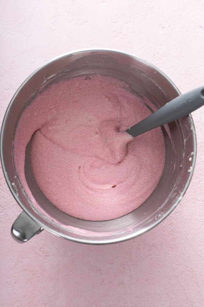adding dry ingredients and champagne into butter mixture in thirds and then pink food coloring being added to make the pink champagne cake.
 