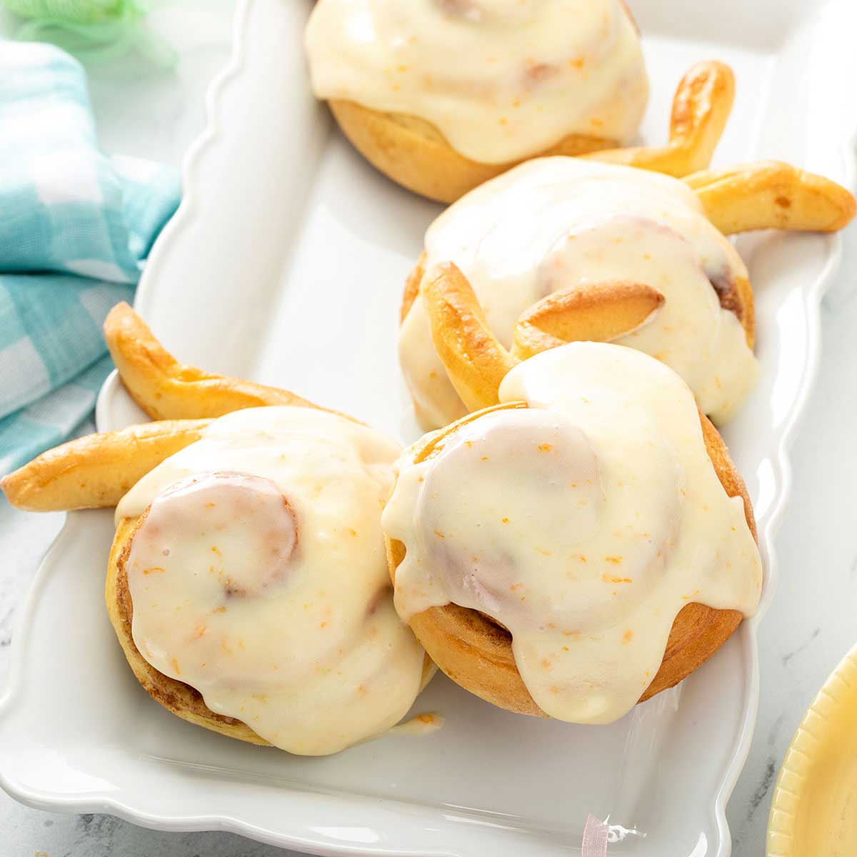 Sweet cinnamon rolls with orange cream cheese glaze on a white plate