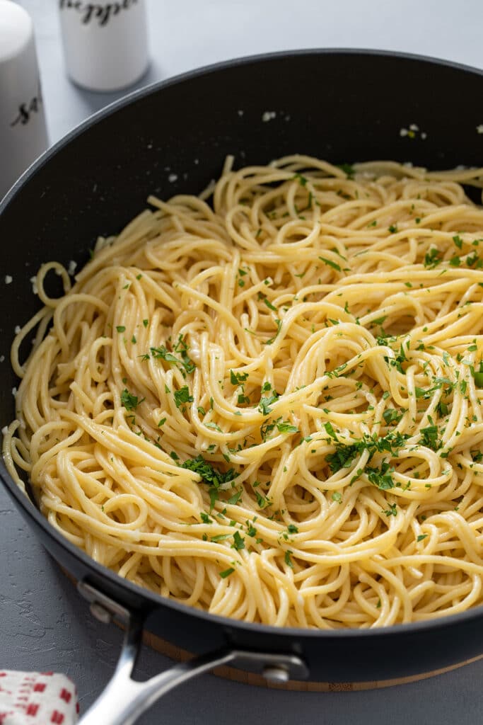 Tossed spaghetti with garlic butter and Parmesan in a skillet.