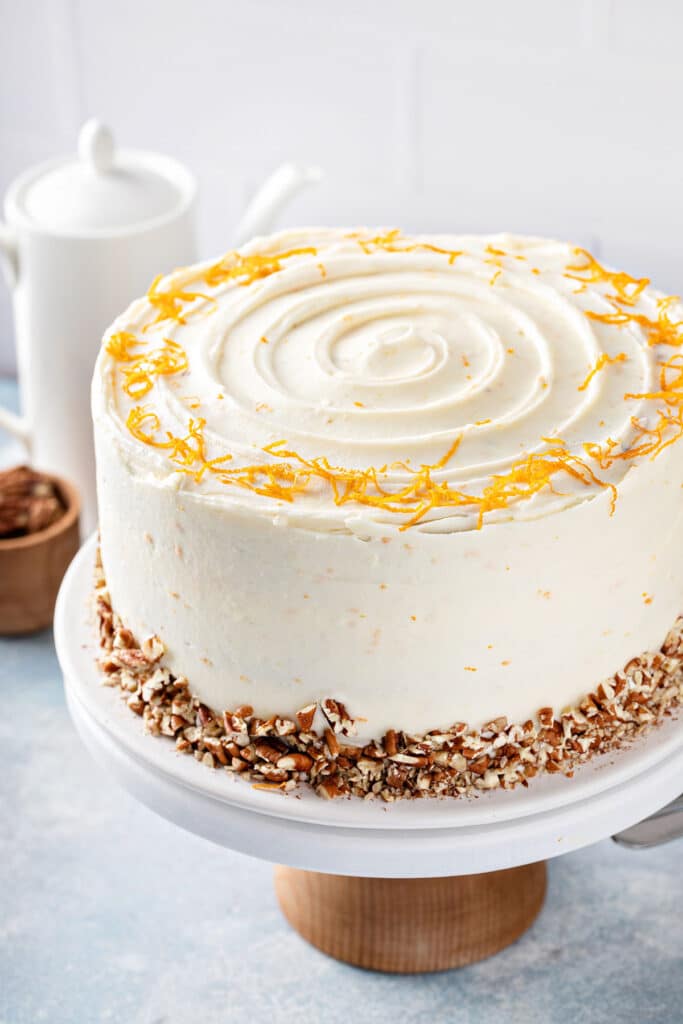 Carrot cake frosted with smooth and silky orange grand marnier cream cheese frosting on a cake stand