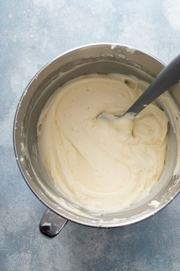Creamy and smooth cream cheese frosting with orange zest and grand marnier liqueur in a mixing bowl