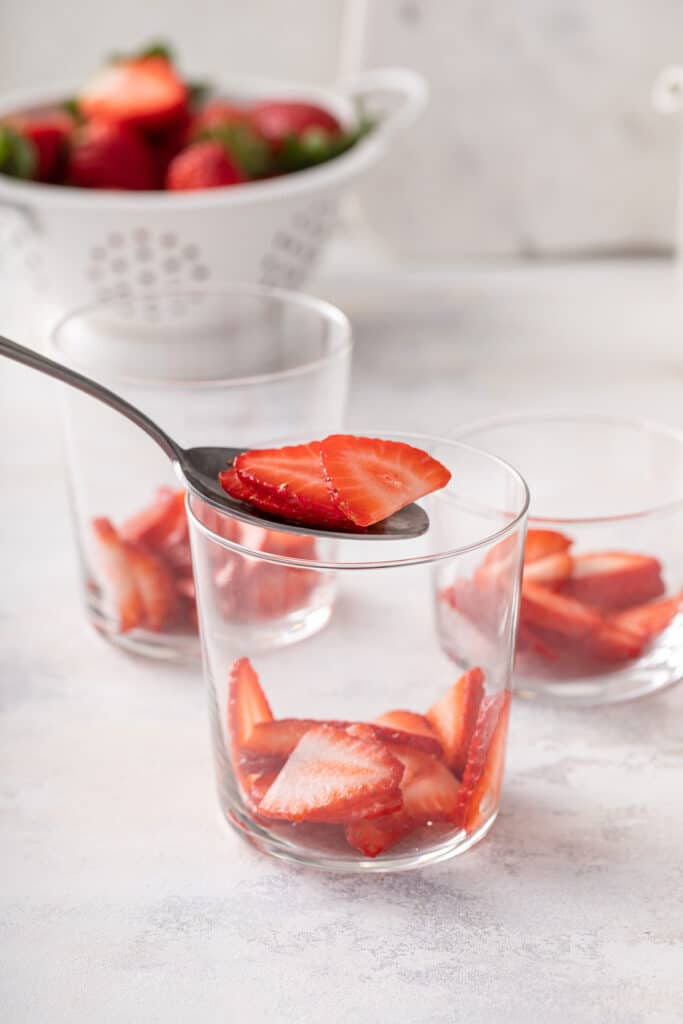 layering fresh cut strawberries in glass 