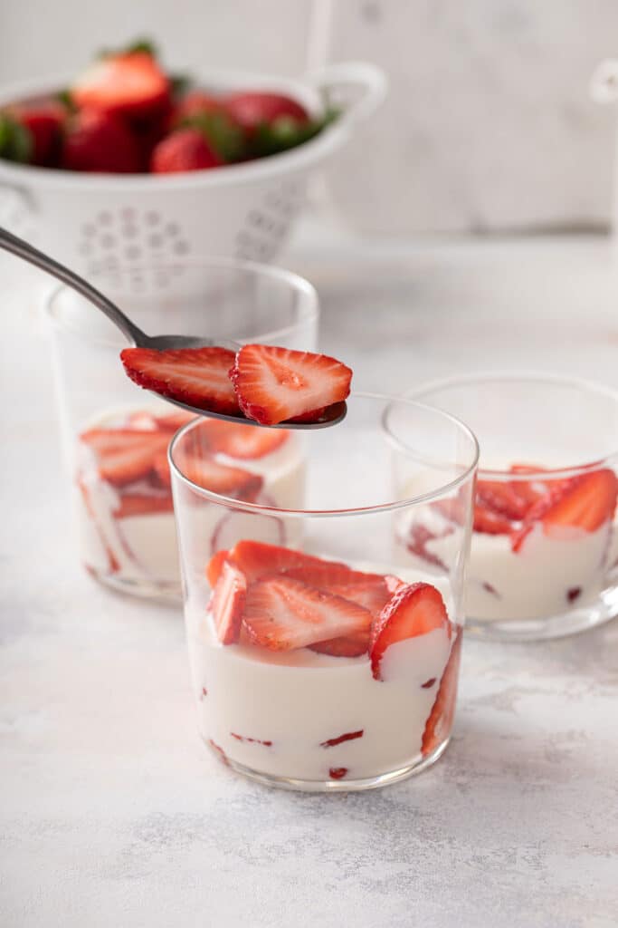 a new layer of red strawberries carefully layered on top of cream mixture of fresas con crema (strawberries and cream)