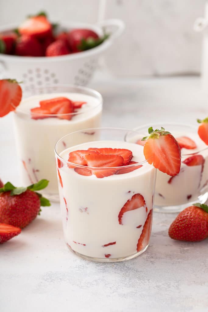Glass filled with sliced strawberries and sweetened Mexican crema sauce.