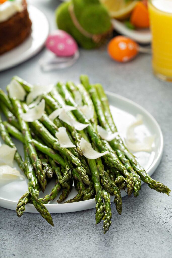 grilled Asparagus topped with Parmesan cheese on a plate