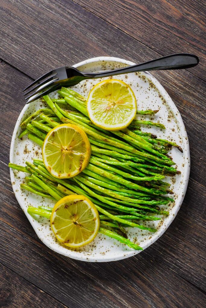 Grilled asparagus topped with lemon sliced on a plate