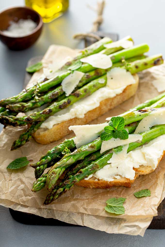 Crostini toast topped with whipped ricotta, grilled asparagus and Parmesan cheese